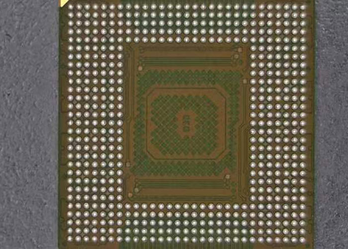 Full bottom view of a BGA (Ball Grid Array) processor chip showing the complete matrix of solder balls and central capacitor array.