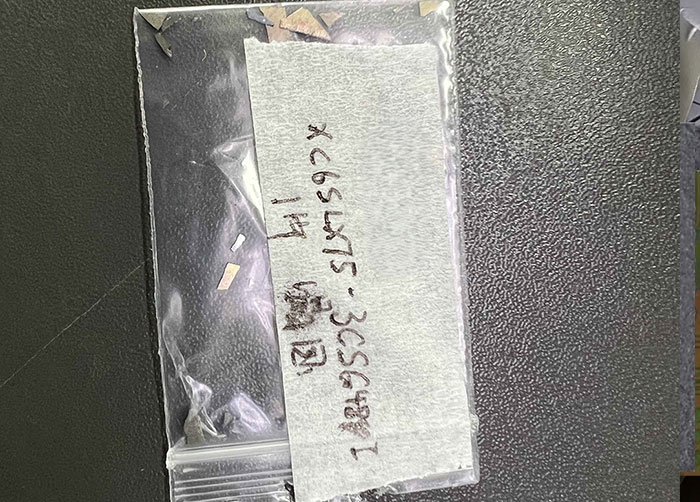 Small plastic bag containing decapsulated chip fragments from a destructive authenticity test of a Xilinx FPGA.