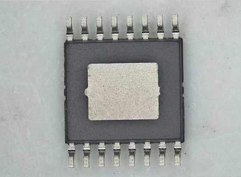 Bottom view of an IC package showing the exposed metal thermal pad and clean lead conditions during inspection.